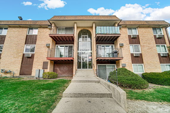 Front view of a multi-story brick apartment building with balconies.