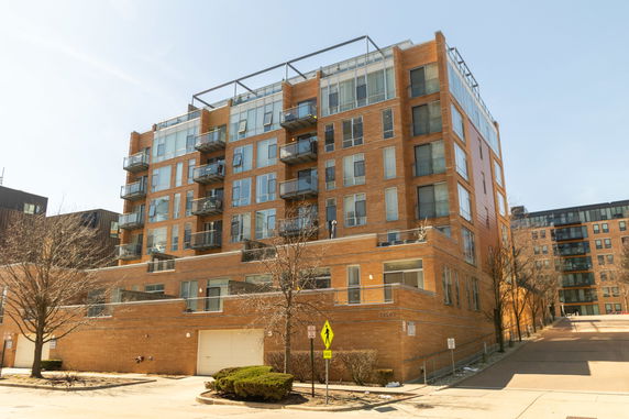 Front view of a multi-story brick apartment building with balconies.