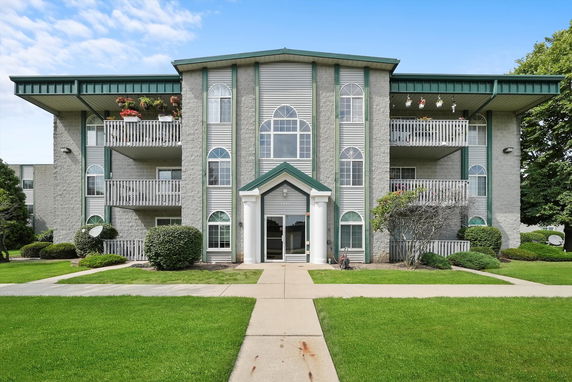 Front view of a three-story residential building with balconies and a central entrance.
