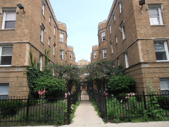 Front view of a multi-story brick building with decorative gate and garden path.