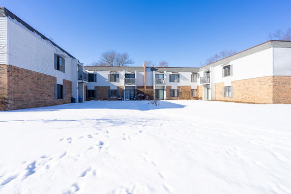 Front view of a two-story building with brick and white siding in a snowy setting.