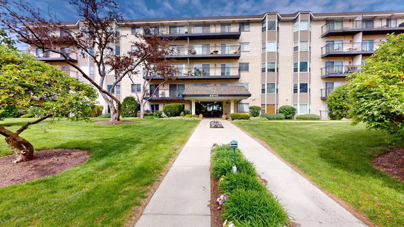 Front view of a multi-story residential building with balconies and a central entrance.