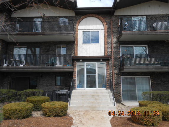 Front view of a multi-story building with balconies and a central entrance.