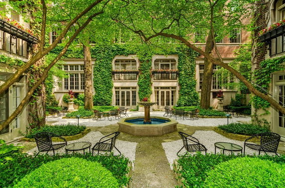 Garden courtyard of a building with ivy-covered walls and outdoor seating.