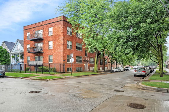 Front view of a three-story brick apartment building with balconies.