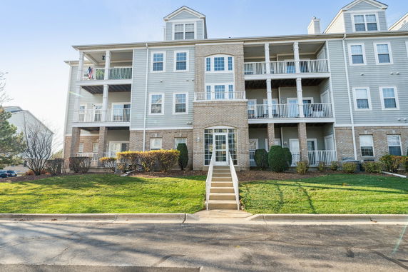 Front view of a multi-story residential building with balconies and a staircase entrance.