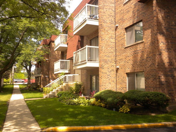Front view of a multi-story brick apartment building with balconies.
