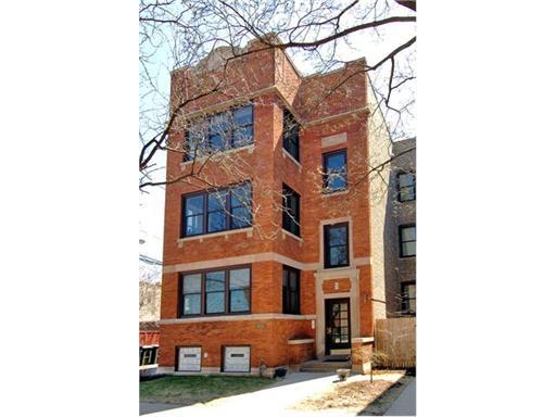Front view of a multi-story brick building with large windows.
