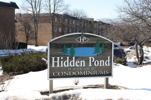 Front view of a condominium building with a sign reading 'Hidden Pond'.