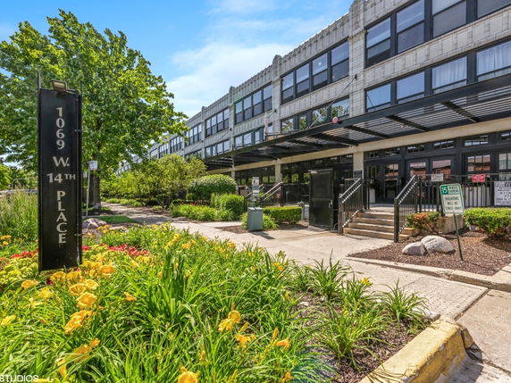 Front view of a multi-story building with large windows and a landscaped entrance.