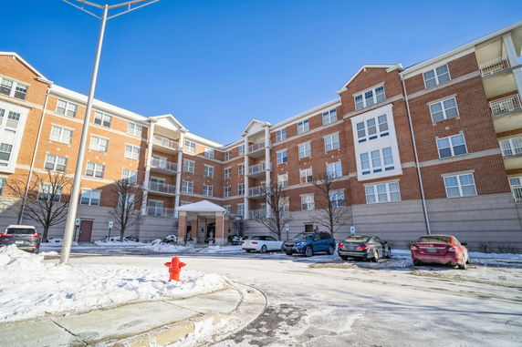Front view of a multi-story brick apartment building with balconies.