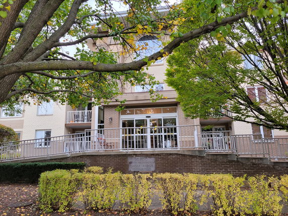 Front view of a multi-story condominium building with balconies and a ramp.