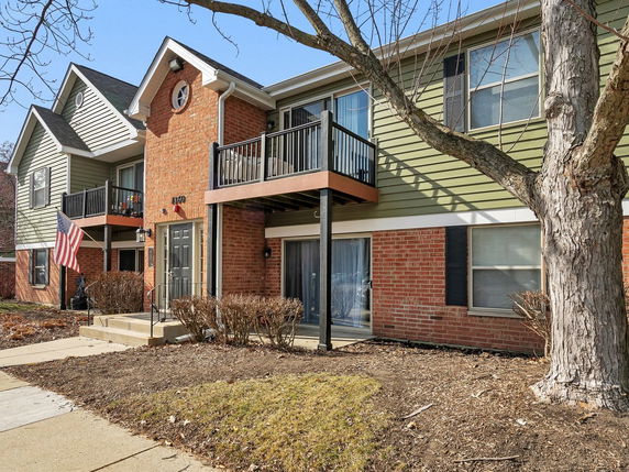 Front view of a two-story house with green siding and red brick accents.