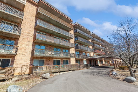Front view of a multi-story building with multiple balconies and a brick facade.