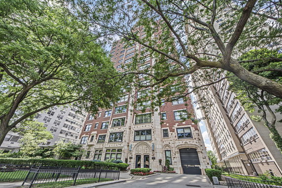 Front view of a multi-story brick apartment building with large windows and detailed entrance.