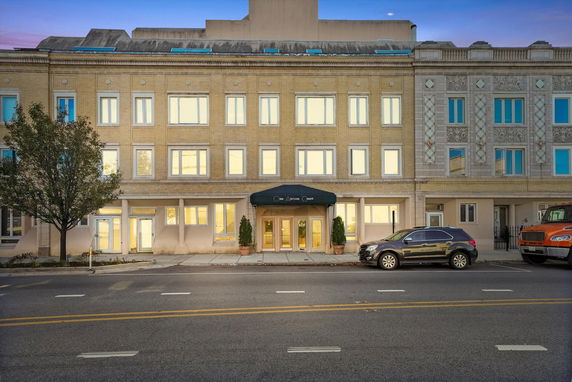 Front view of a multi-story building with large windows and columns at the entrance.