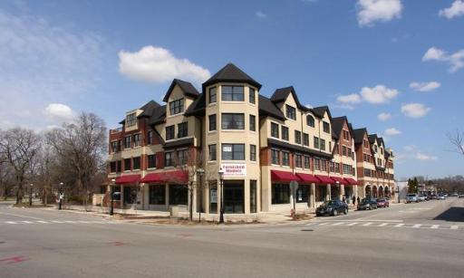 Front view of a multi-story building with shops on the ground floor and residential units above.