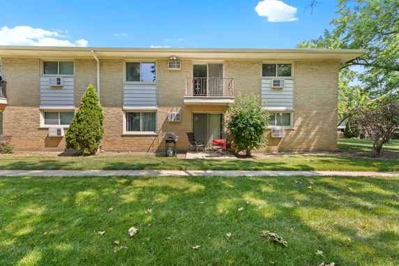 Front view of a two-story brick apartment building with balconies and air conditioning units.