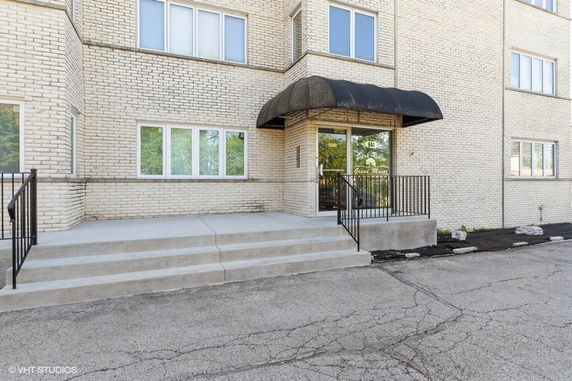 Entrance of a brick building with steps leading to a glass door and black canopy.