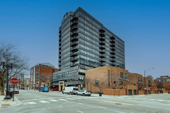 Front view of a multi-story building with glass windows and balconies.