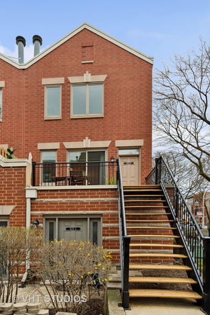 Front view of a two-story brick building with large windows and an outdoor staircase.