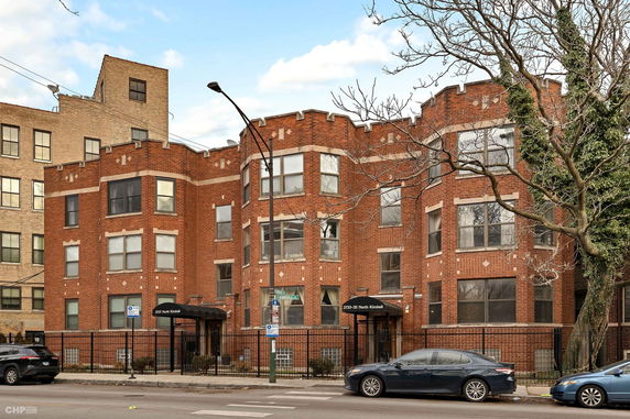 Front view of a multi-story brick building with bay windows and decorative cornices.
