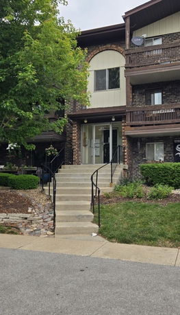 Front view of a three-story residential building with brick exterior and balconies.