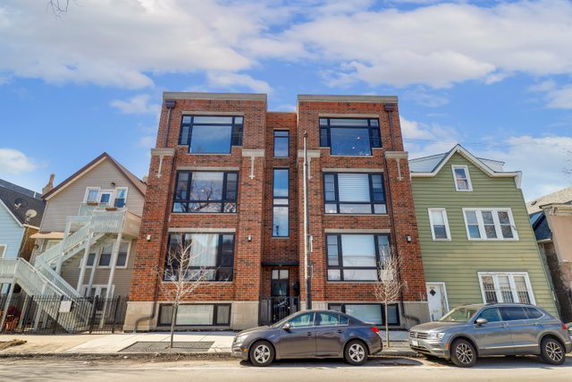 Front view of a three-story brick apartment building with large windows.