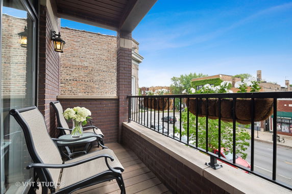 Balcony view showing chairs, flowers, and a street scene.