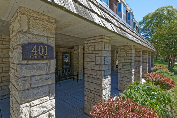 Front view of a building with stone columns and a sign displaying '401 Ascot Drive'.