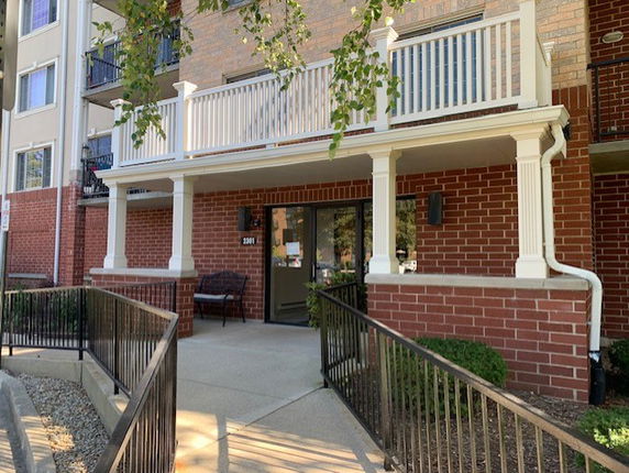 Front entrance of a brick apartment building with a porch and railing.