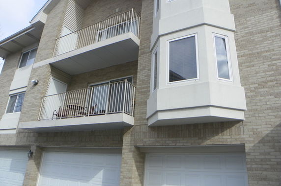 Front view of a multi-story residential building with balconies and a garage.