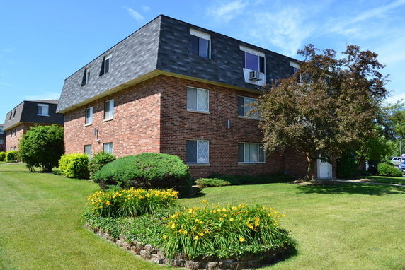Front view of a multi-story brick apartment building with a dark roof.