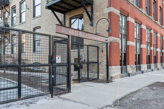 Front view of a multi-story loft building with a gated entrance.