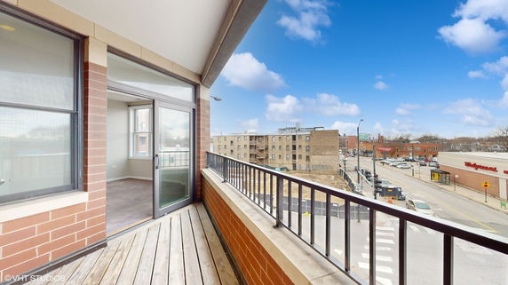 Panoramic view from a building balcony overlooking a street and surrounding buildings.