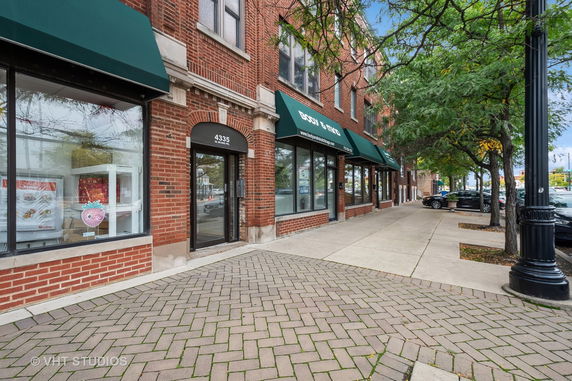 Front view of a commercial building with a brick exterior and green awnings.