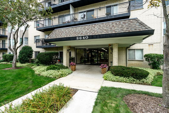 Front view of a multi-story building with balconies and entrance canopy.