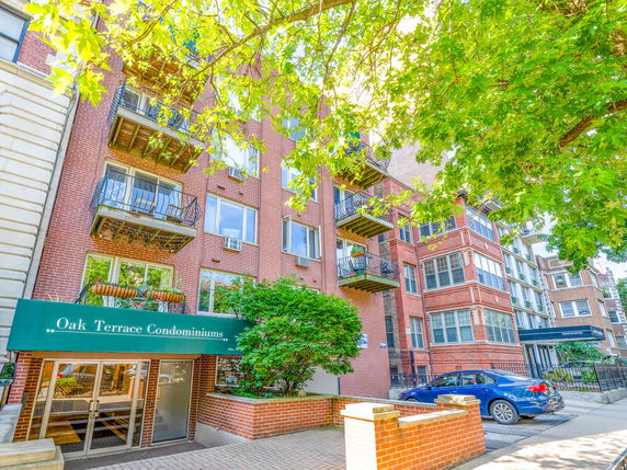 Front view of Oak Terrace Condominiums, a multi-story brick apartment building with balconies.