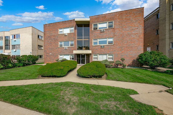 Front view of a three-story brick apartment building with a central entrance.