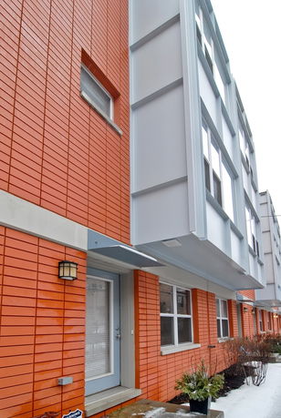 Front view of a modern multi-story building with orange brick facade and gray accents.