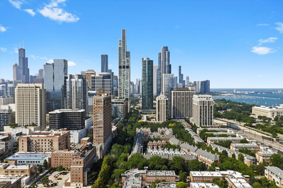 Aerial view of a city skyline with numerous high-rise buildings and a body of water in the distance.