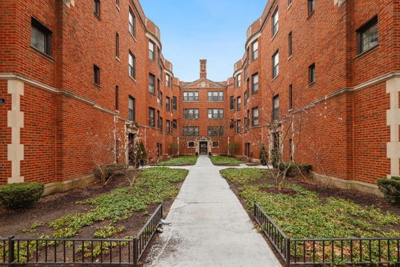 Front view of a multi-story brick apartment building with a central walkway.