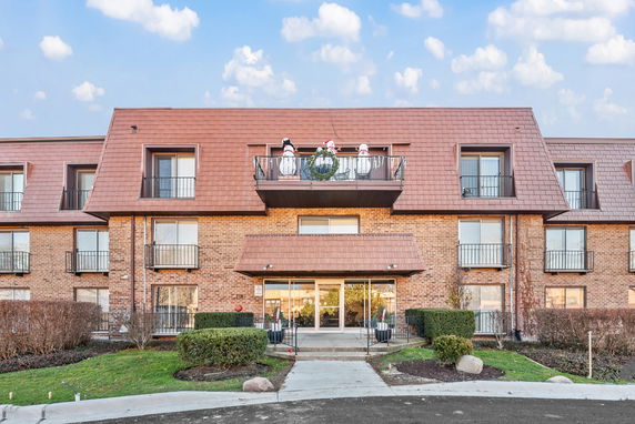 Front view of a multi-story building with a balcony and brick exterior.