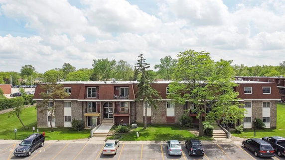 Front view of a multi-story apartment building with parked cars.