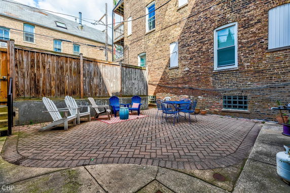 Outdoor patio area with chairs and a table against a brick building.