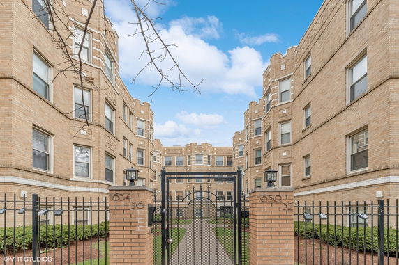 Front view of a brick apartment building with a gated entrance.