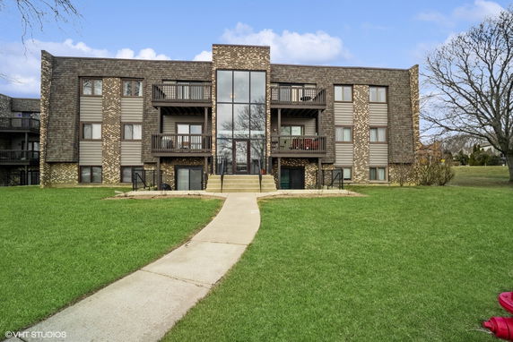 Front view of a multi-story building with balconies and a central glass entrance.