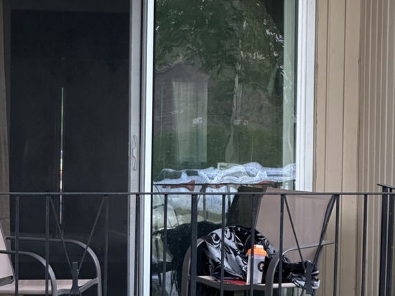 Front view of a house with a metal railing and a sliding glass door.