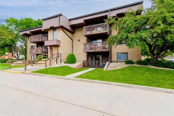 Front view of a two-story apartment building with balconies and a sloped walkway.