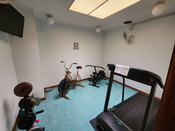 Small indoor gym with exercise equipment including a treadmill and stationary bike.